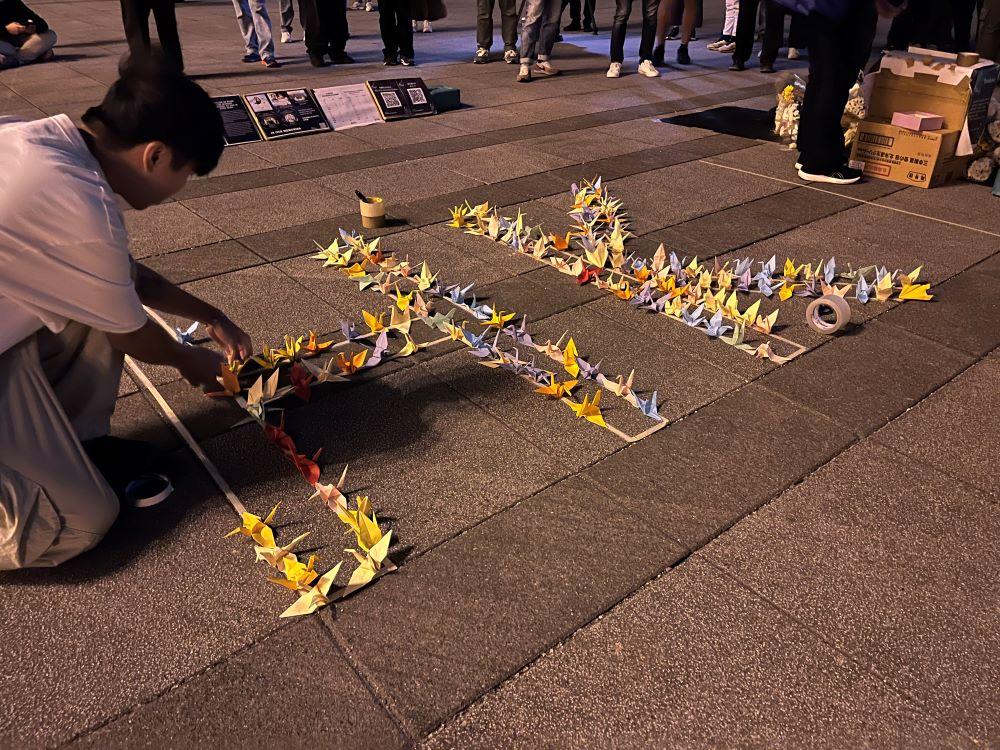 民眾以紙鶴在地上排出HK香港字樣。(圖/中央社)