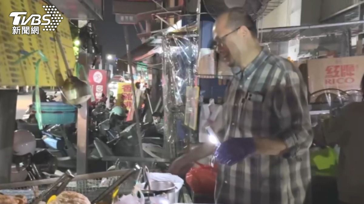 滷味攤商靠手電筒克難營業。(記者 陳奇君攝)