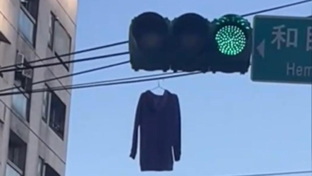 民眾開車經過路口時,發現紅綠燈後的電線上竟掛著一件衣服。(圖/Threads@yt._.96)