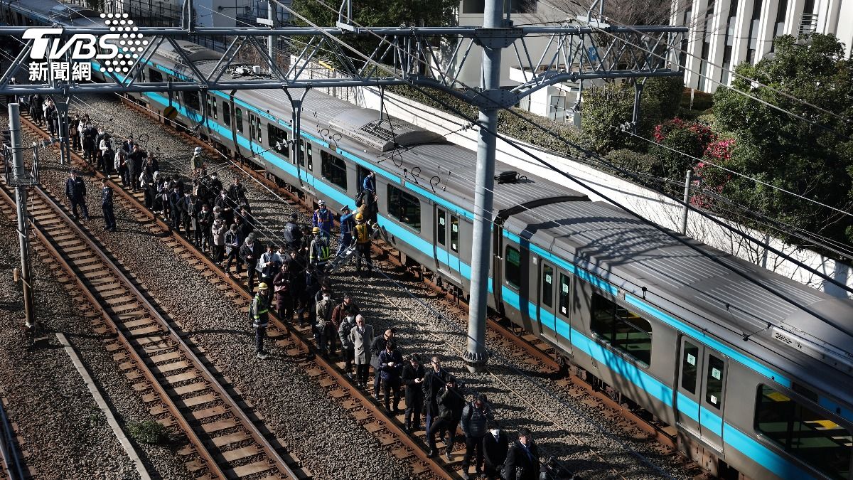 京濱東北線列車因停電停駛,乘客下車步行沿軌道前往東京田町站。(圖/達志影像路透社)