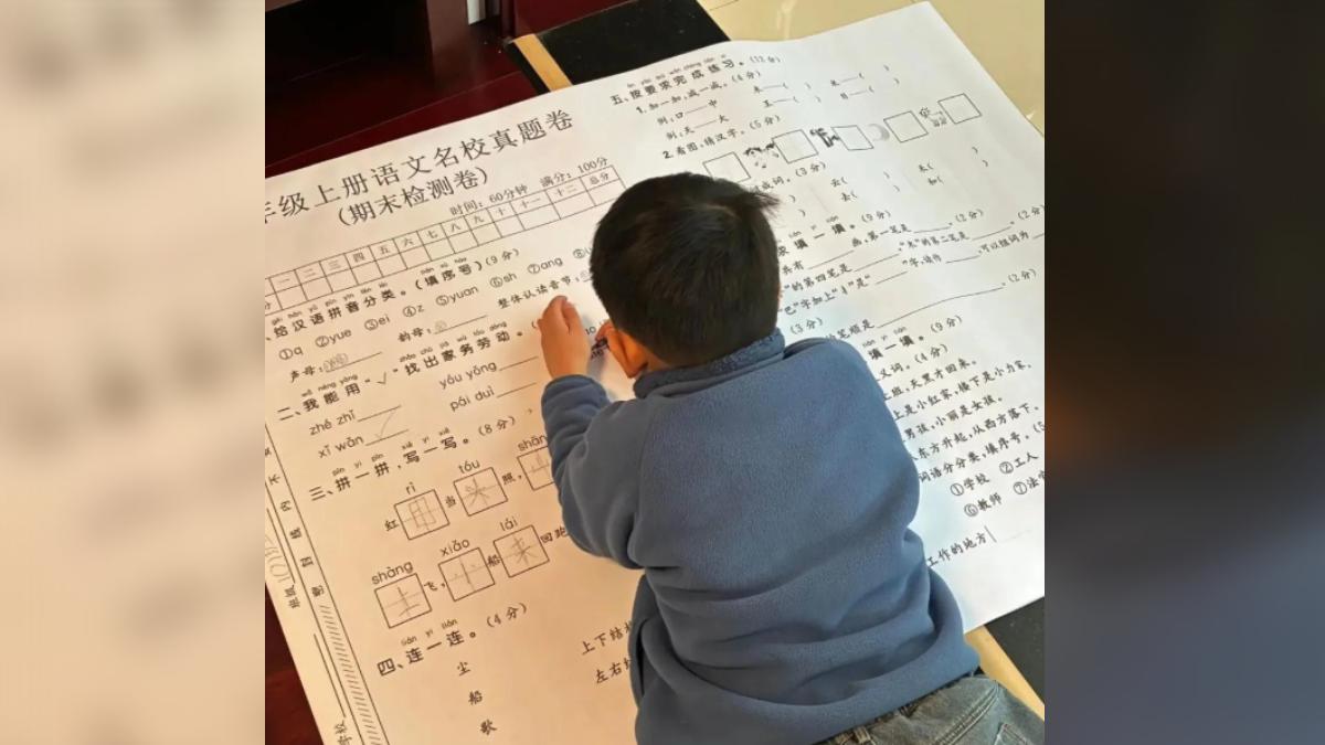 孩子在地上作答「A0尺寸」寒假練習卷。(圖/翻攝網易)