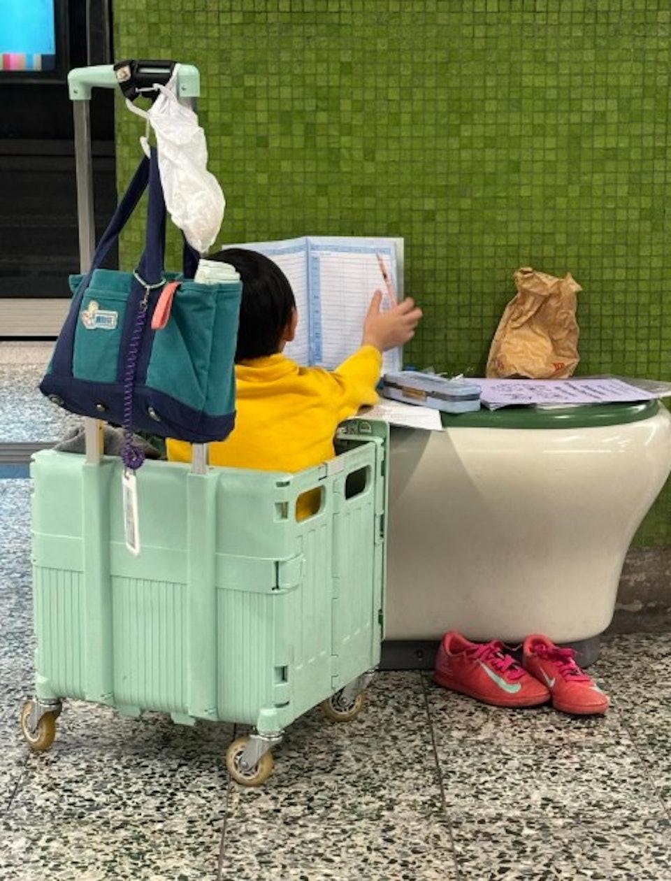 男童坐在手推車內,把月台座位當書桌寫功課。(圖/翻攝自threads@1211.jenn)
