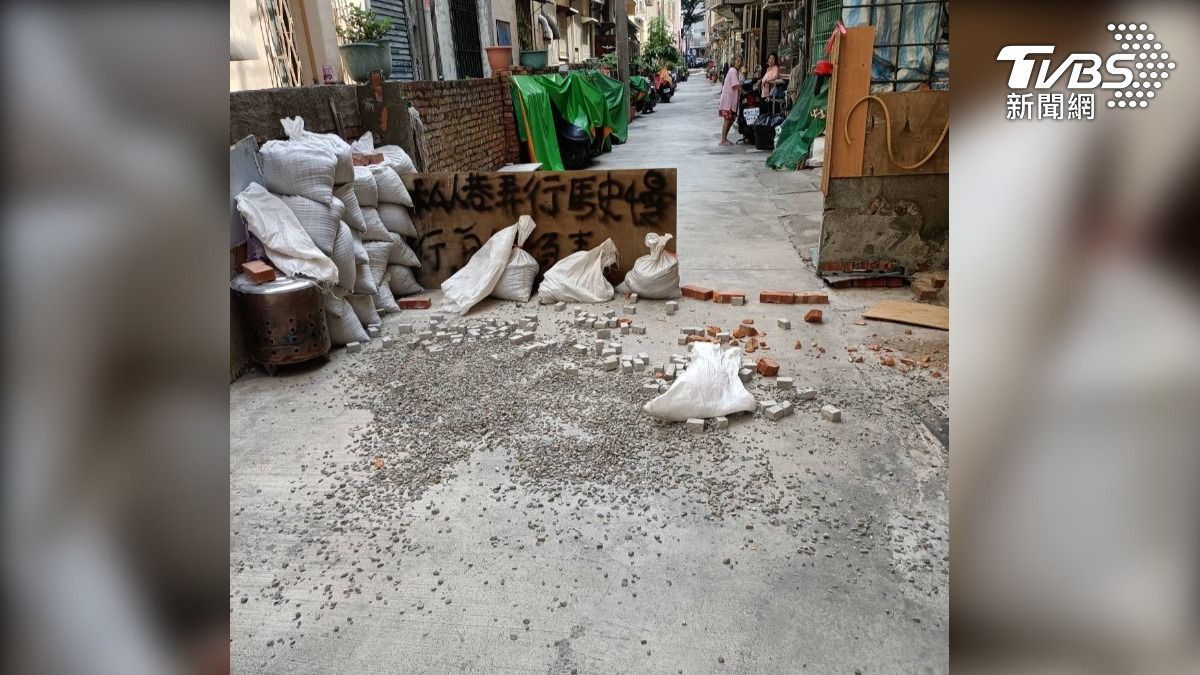 巷道內被圍了三分之二，地上還鋪滿碎石，甚至牆壁上還噴漆寫了不雅字眼，都是在惠民捷道打人的馬姓清潔員所為（圖／TVBS）