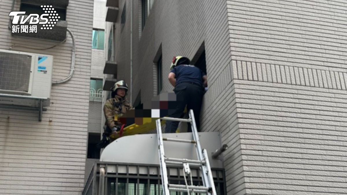高雄一名羅姓男子酒後墜樓,倒臥在採光罩上,消防人員急忙架梯上去急救。(圖/TVBS)