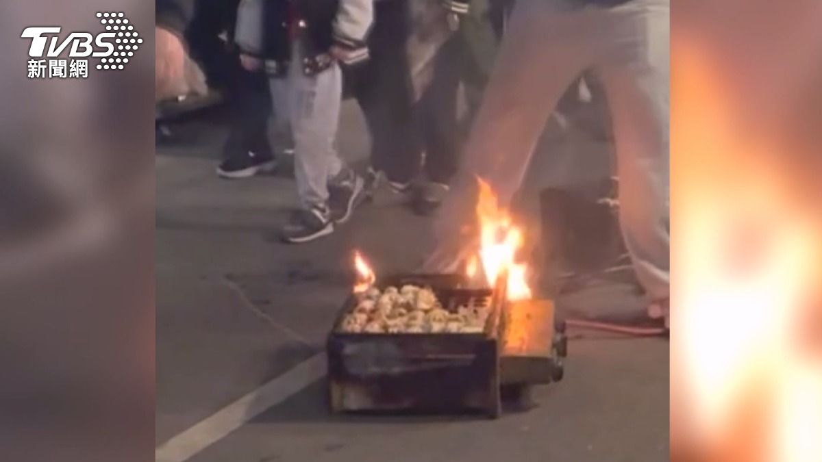 章魚燒攤位的爐具突然起火燃燒,店家緊急將整台爐具搬至通道中央試圖滅火。(圖/民眾提供)