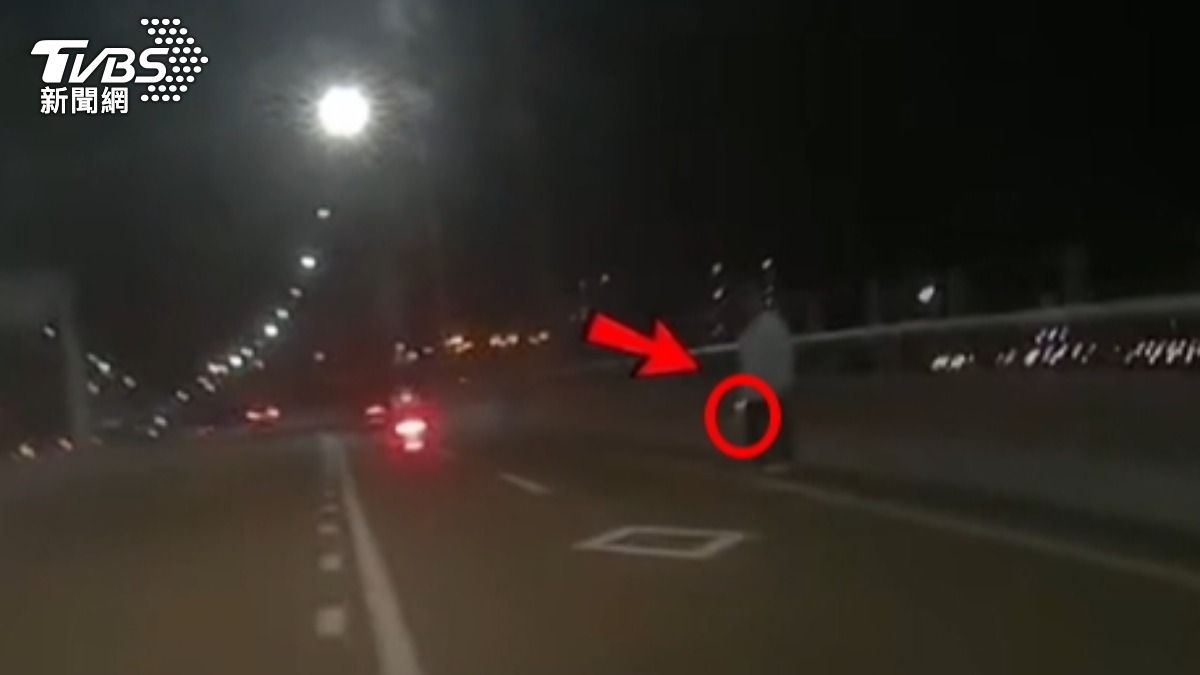 女子手緊握「反光不明物體」站機車道旁!路人嚇報警,疑包包反光惹誤會。(圖/TVBS)