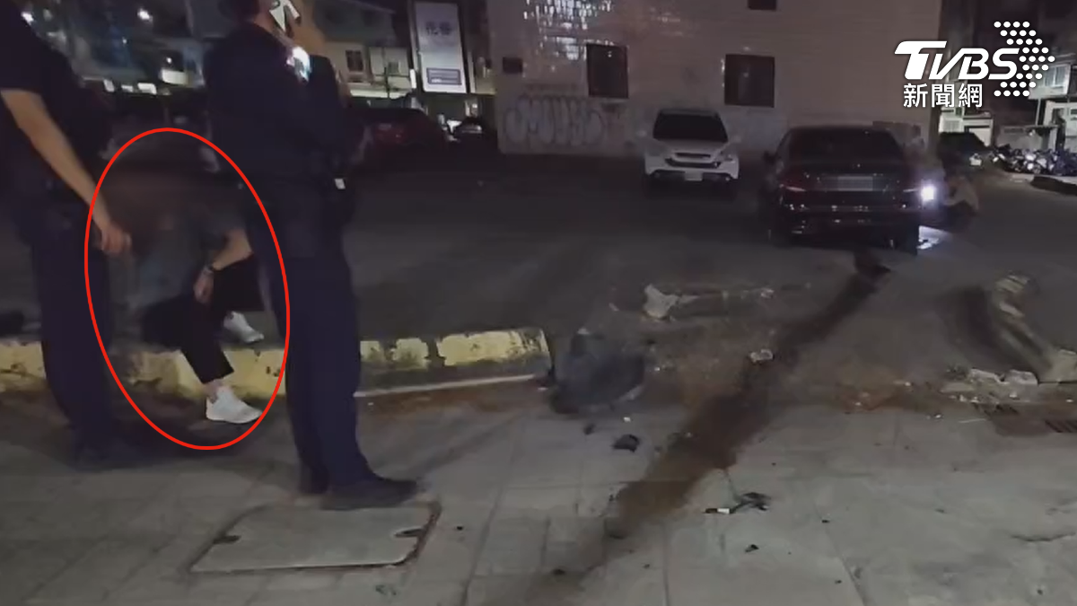 肇事駕駛走路走不穩才要扶著員警的腰,坐在一旁休息,頻頻扶著額頭(圖/TVBS)