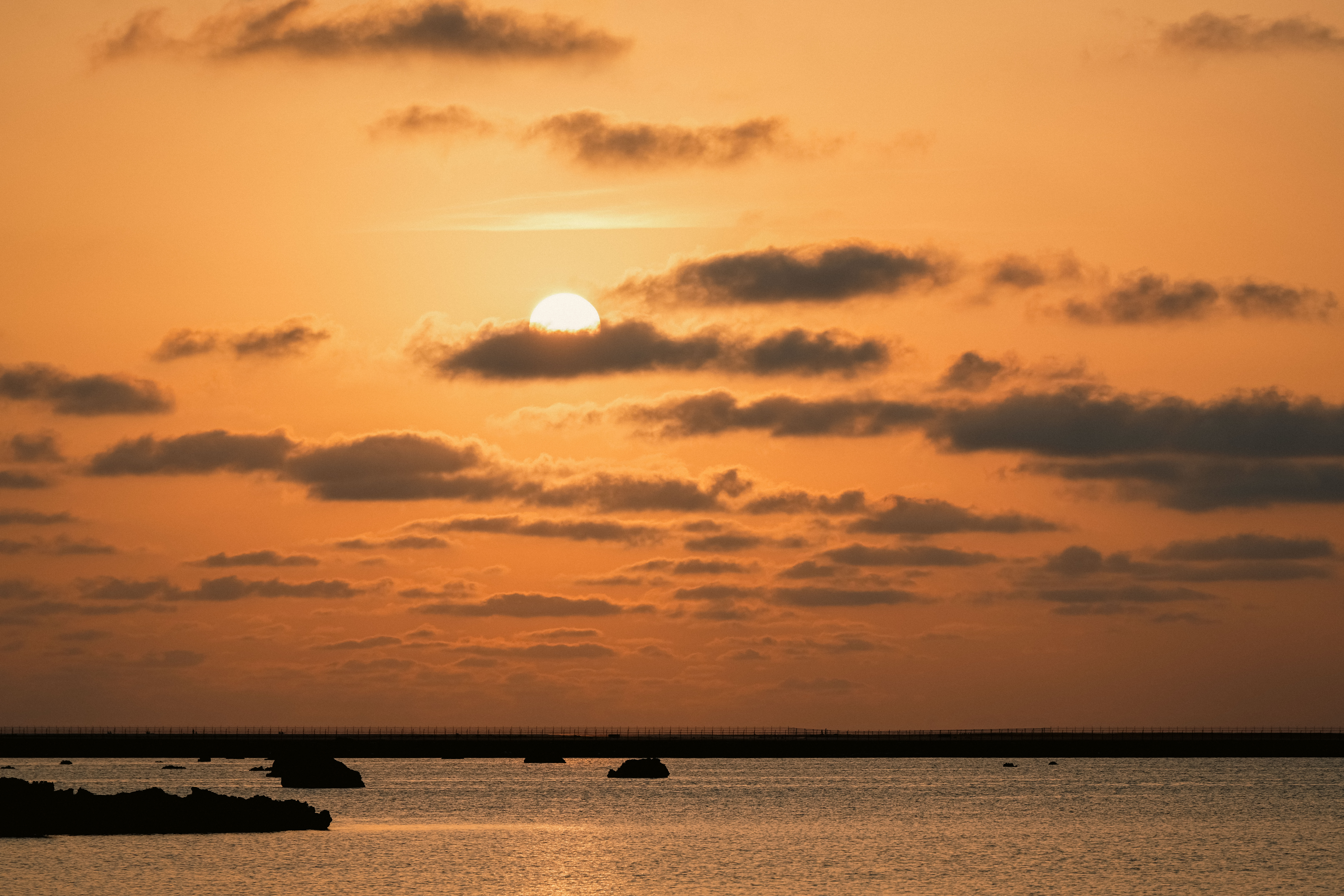 夕陽落入宮古島佐和田之濱的海面,橘金色光暈映照海岸線之美。