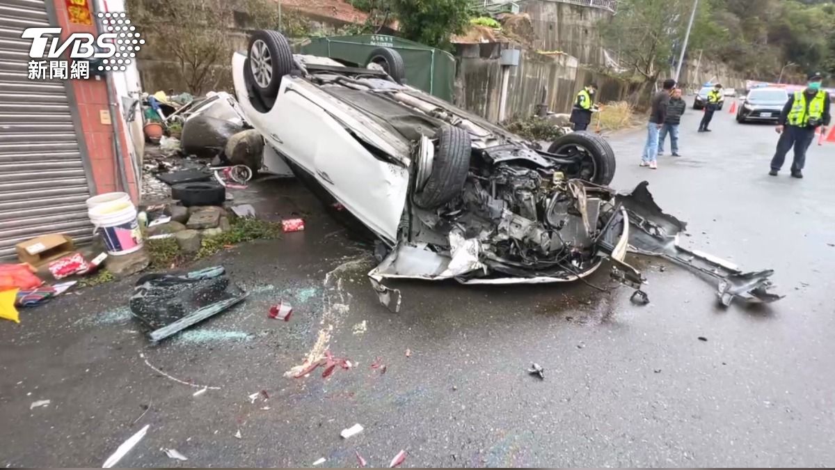 白色轎車過彎後失控翻車，四輪朝天停在民宅旁空地，現場撞開一堆物品，一片混亂。(圖／TVBS)