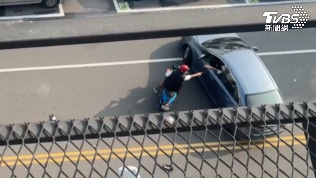 除了修車廠人員外,現場還有一名戴著安全帽的機車騎士幫忙安撫鄒姓男子的情緒。(圖/TVBS)