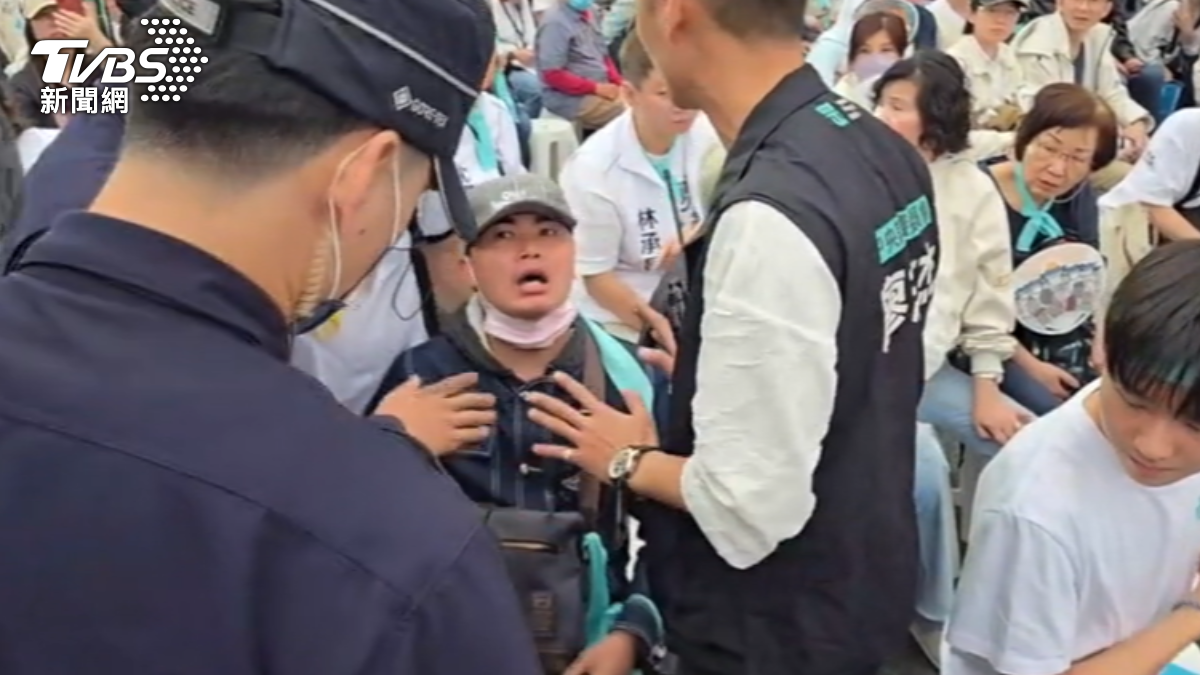 吃屎哥戴著水藍色飄帶潛入遊行鬧場,當場遭大批警力抬走。(圖/TVBS)