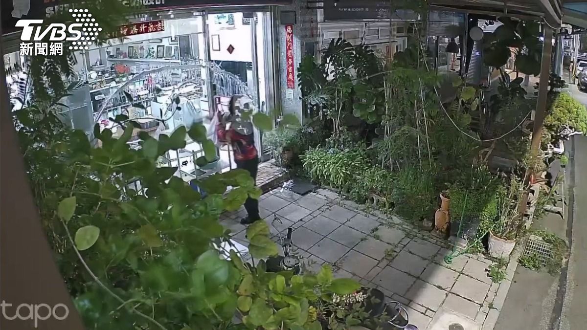 陌生女子全身遮掩嚴密,趁事務所內無人之際,拿著白色油漆四處潑灑。(圖/民眾提供)