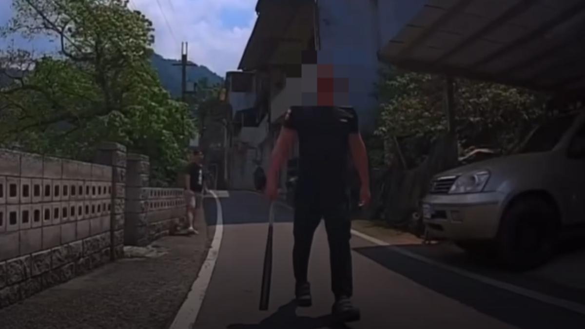 男子拿著球棒，攔截騎士的無辜友人不准離開，要求當事人折返道歉。（圖／TVBS）