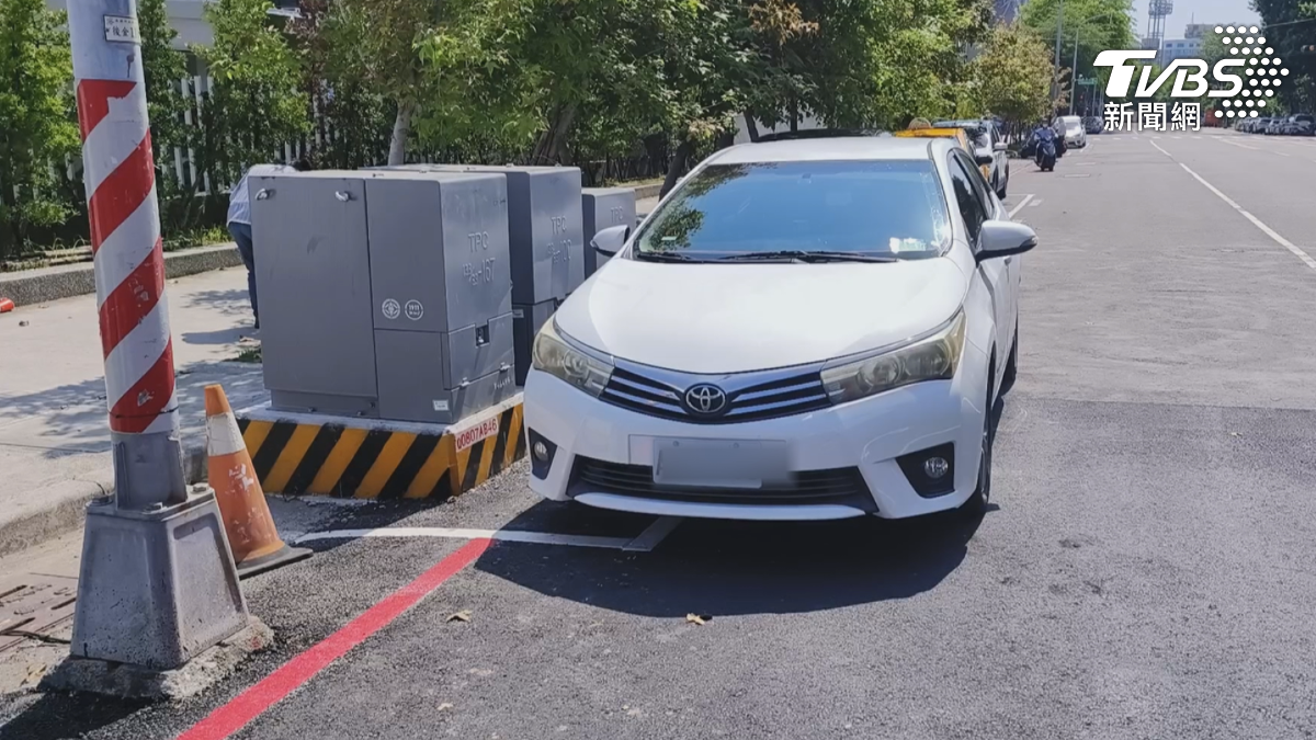 高雄市區一處停車格放了變電箱,車子有一半露在外面,駕駛嘆心酸。(圖/TVBS)