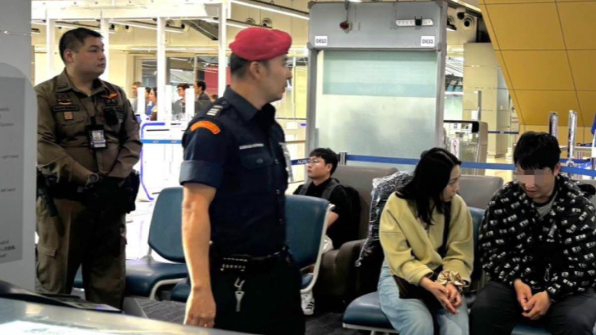 事件發生後,一名中國男子(右)正在和妻子交談,機場安保人員在一旁觀看。 (圖/翻攝《Bangkok Post》)