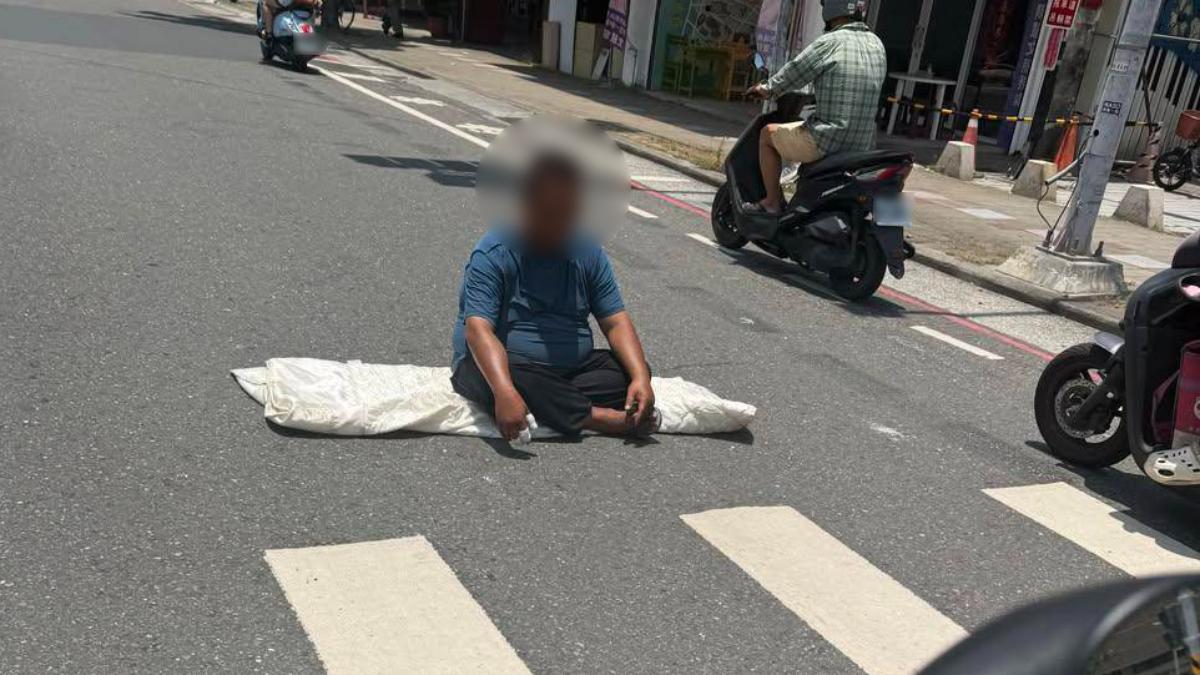 高雄鳳山一名53歲謝姓男子手持菜刀坐在路中央,對路過人車作勢攻擊。(圖/翻攝Threads_yiwen0706)