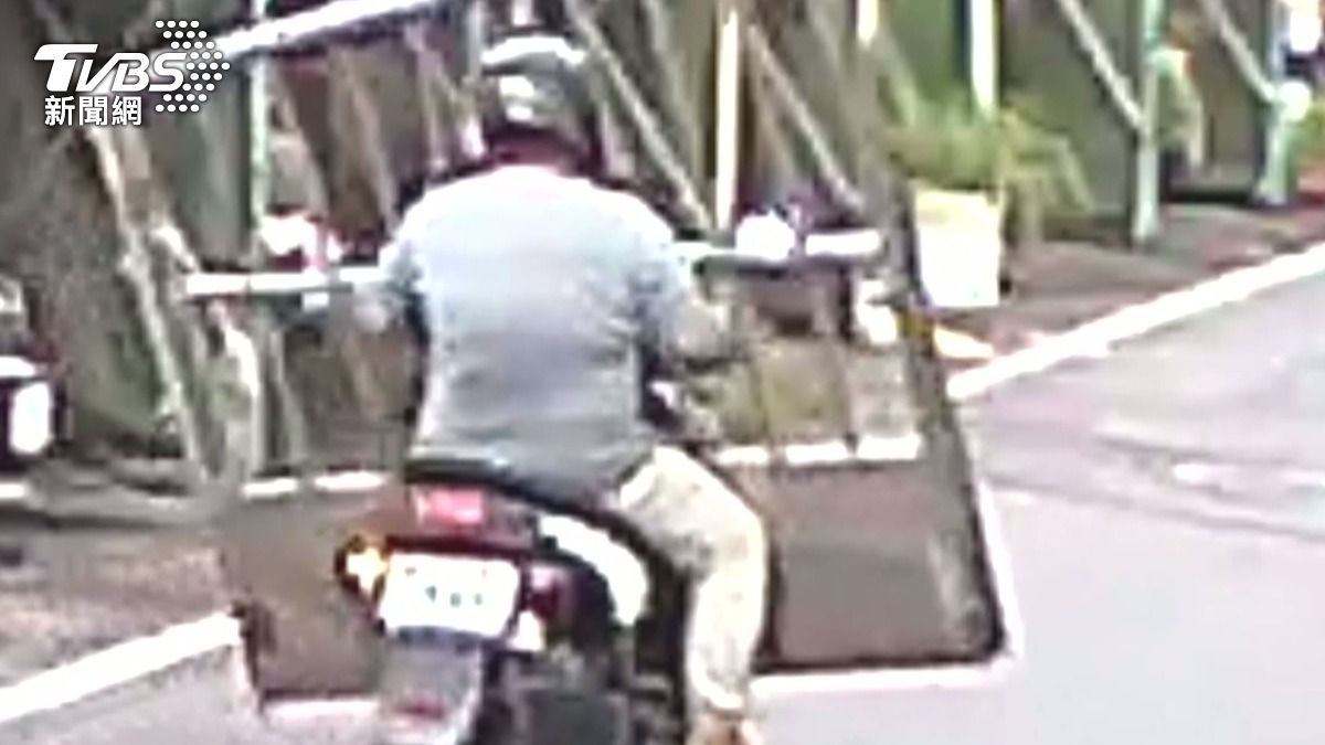 這名騎士載著鐵門行駛,頭部雙手也從縫隙伸出握著機車龍頭,整個人彷彿被關在移動的鐵窗中。(圖/TVBS)