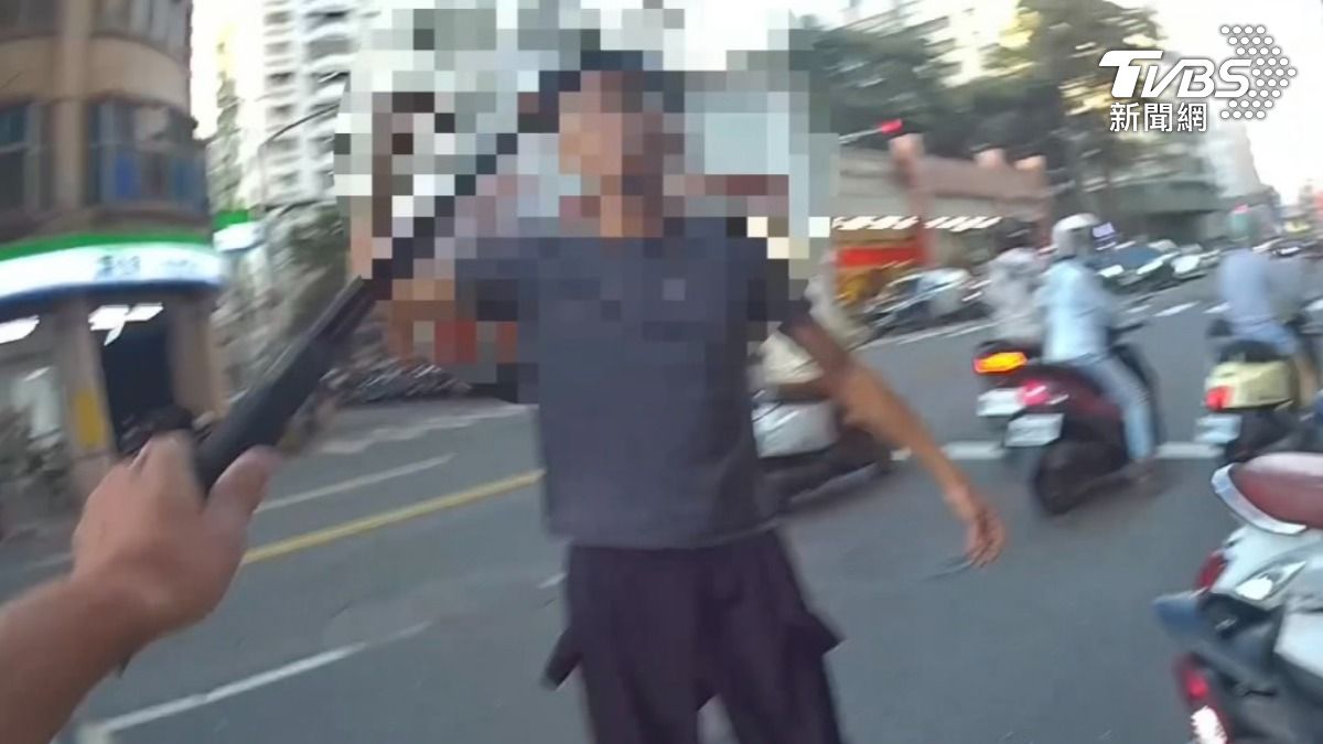 高雄楠梓一名男子情緒失控,右手高舉扳手朝警方步步逼近,一旁支援警力見狀立刻上前攔阻。(圖/TVBS)