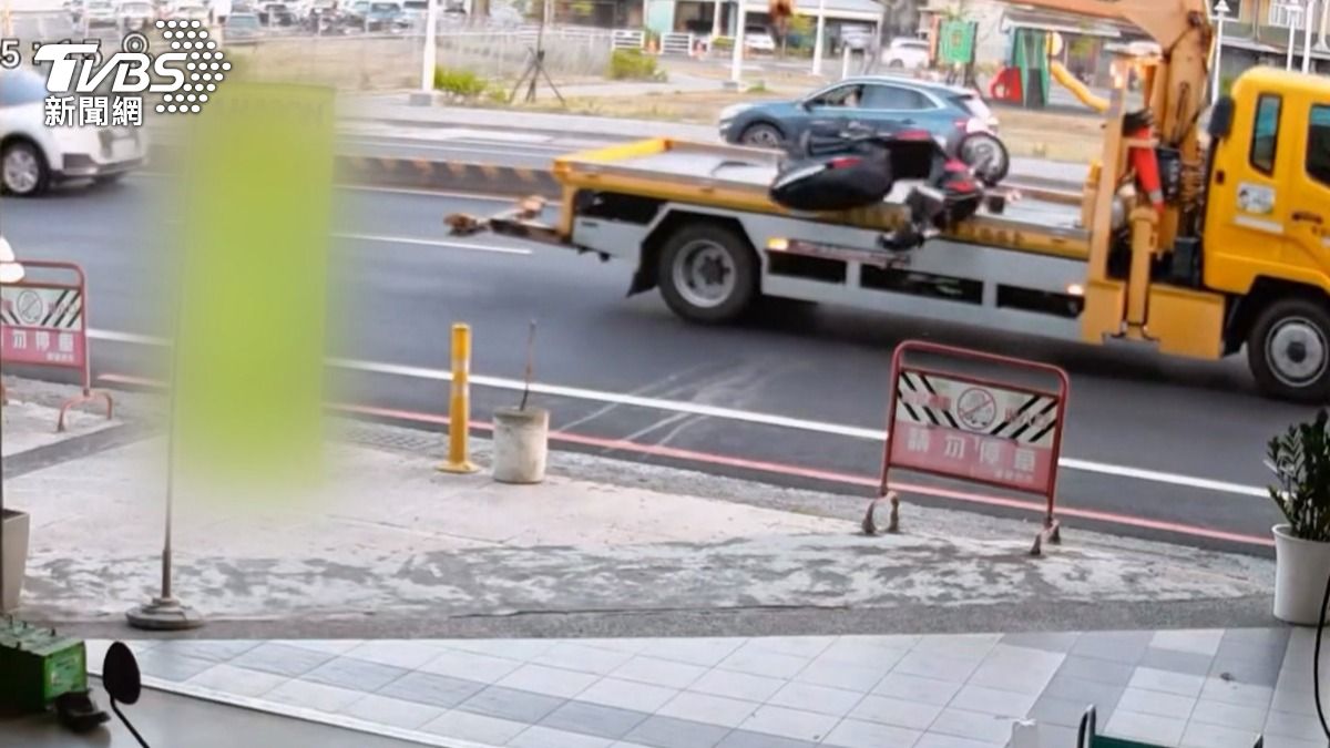 台南東區東門路一段,一部拖吊車載運機車時,疑似沒有固定好,整輛機車倒頭栽翻轉摔到路面上,周邊店家都嚇一跳。(圖/TVBS)