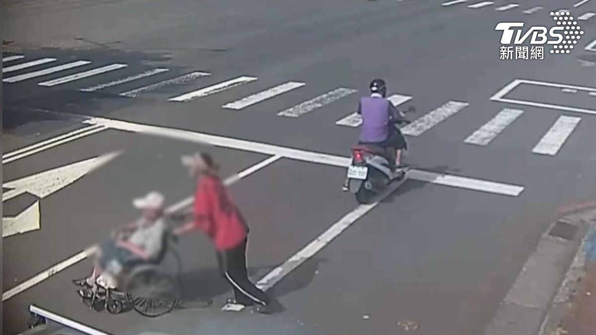 帶著遮陽帽的婦人,推著坐輪椅的阿公出了巷弄後,沒走斑馬線,也不走人行道,直接推著阿公逆向往快車道走(圖/TVBS)