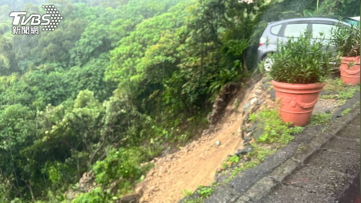 停放路邊的汽車隨著土石崩塌半懸邊坡。(圖/TVBS)