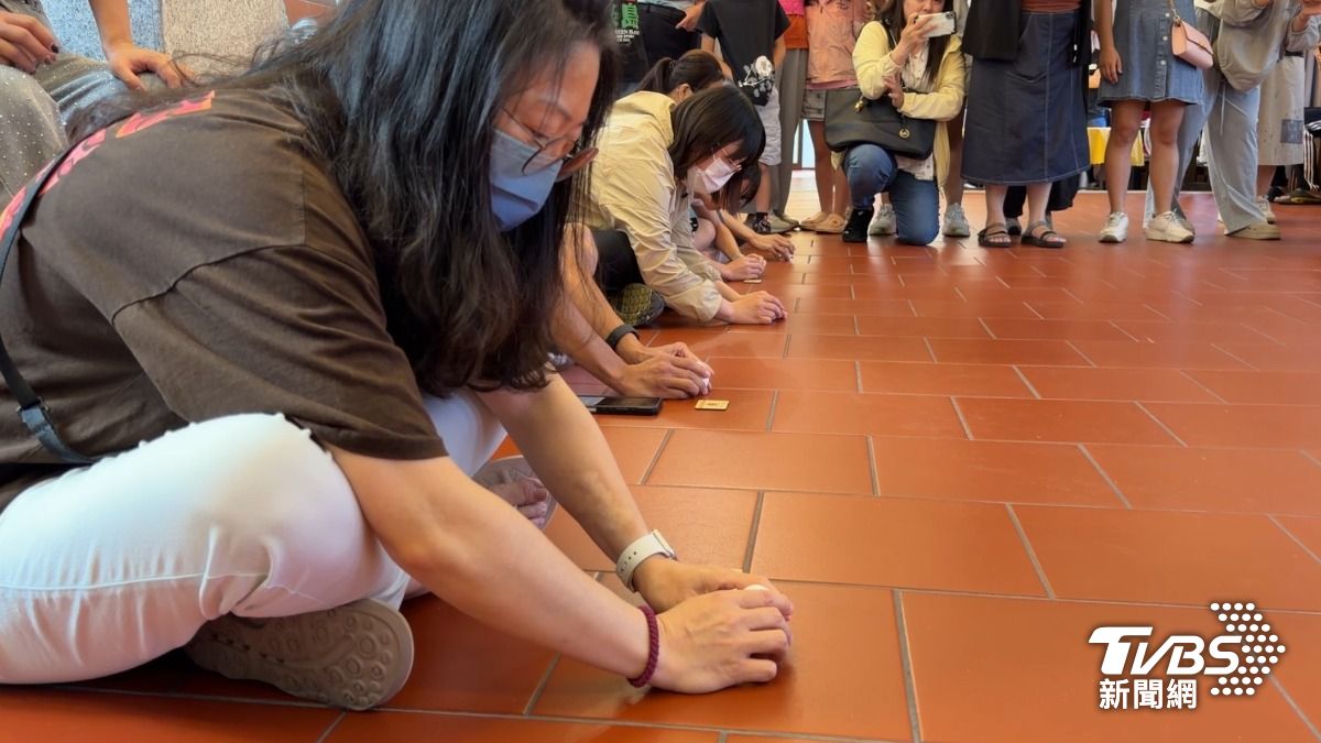 民眾低頭專注立蛋,與旁邊參賽者比速度。(圖/程子奕攝)