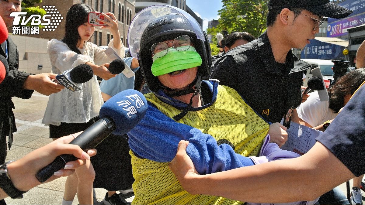 阿伯情緒失控,遭警方強制拉進車內。(圖/胡瑞麒攝)