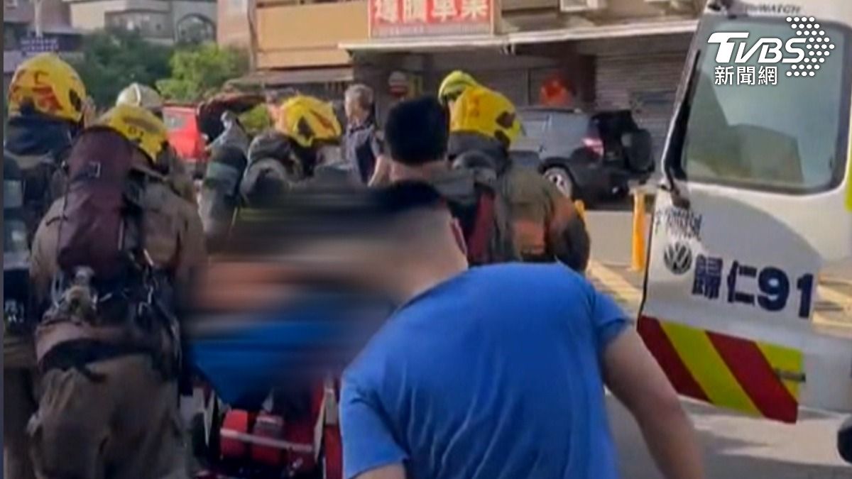 消防人員全副武裝衝入火場，緊急抬出一名命危員工，與時間賽跑連忙送上救護車。（圖／TVBS）