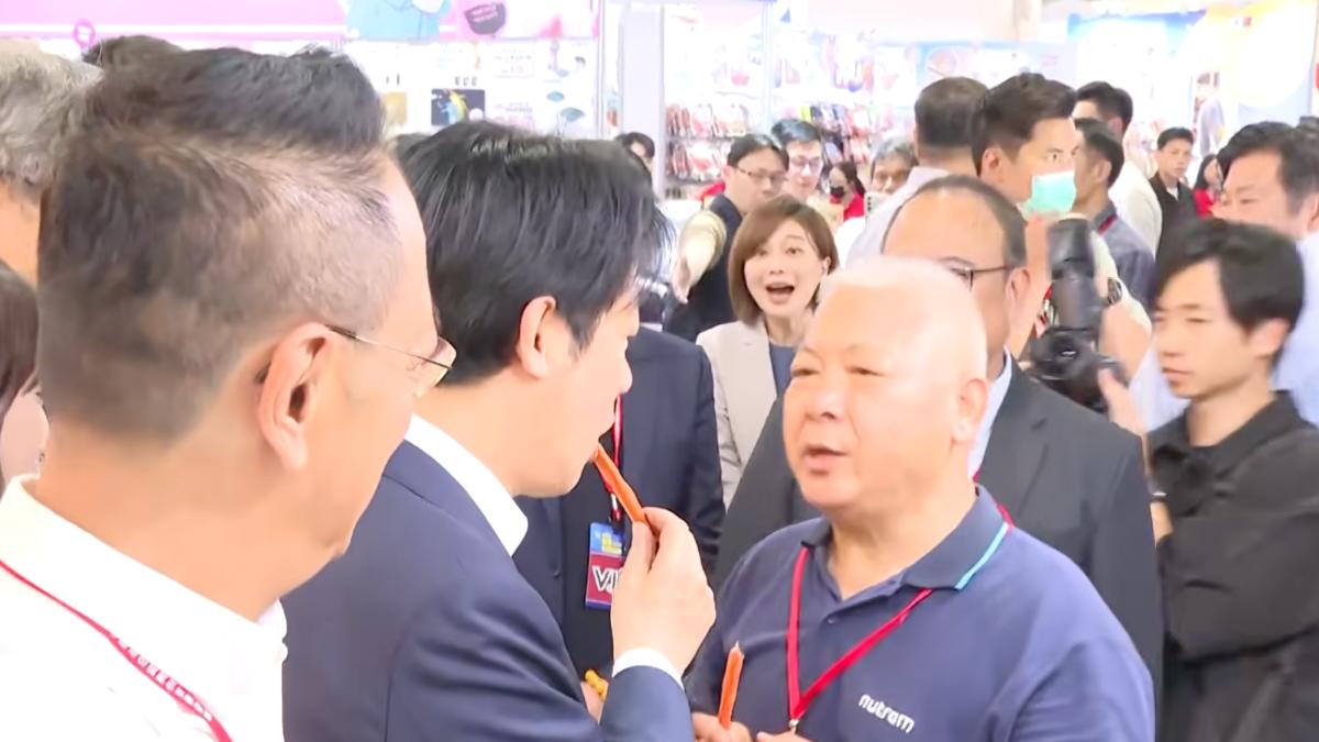 賴清德將狗糧塞進嘴裡，一旁的發言人郭雅慧一臉震驚。（圖／共訊畫面）