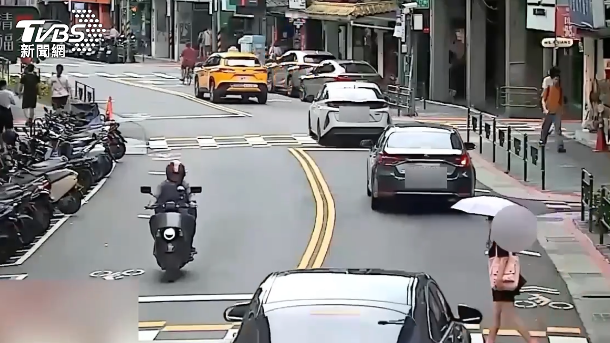 吳姓婦人撐傘過馬路時,遭黑色賓士車撞上。(圖/TVBS)