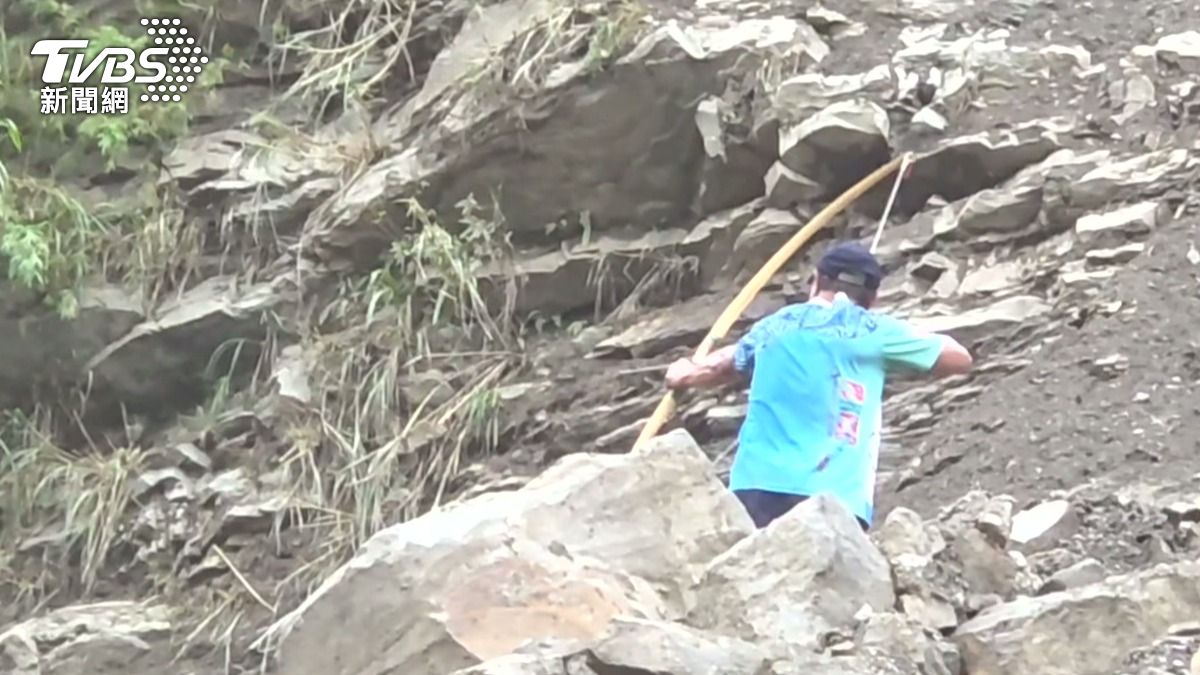 部落居民在石堆上拉弓射箭,一箭射出超過30公尺的繩索,成功搭起補給線。(圖/TVBS)