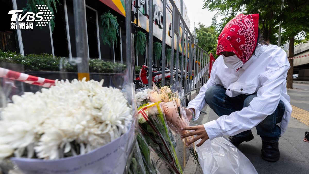 泰國首都曼谷一家啤酒餐廳近日發生嚴重火災，造成多人死亡，一名男子在該店家外擺放鮮花。(圖／達志影像美聯社)