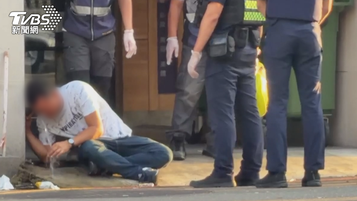 男子被辣椒水嗆得不斷咳嗽,坐在路旁不斷用水沖洗,救護人員也到場協助處理。(圖/TVBS)