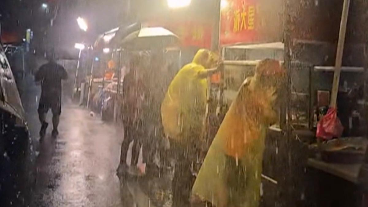 台東夜市颳風下雨,攤販身穿雨衣,兩人緊拉攤車以防被強風吹走。(圖/翻攝Threads___meow28__)