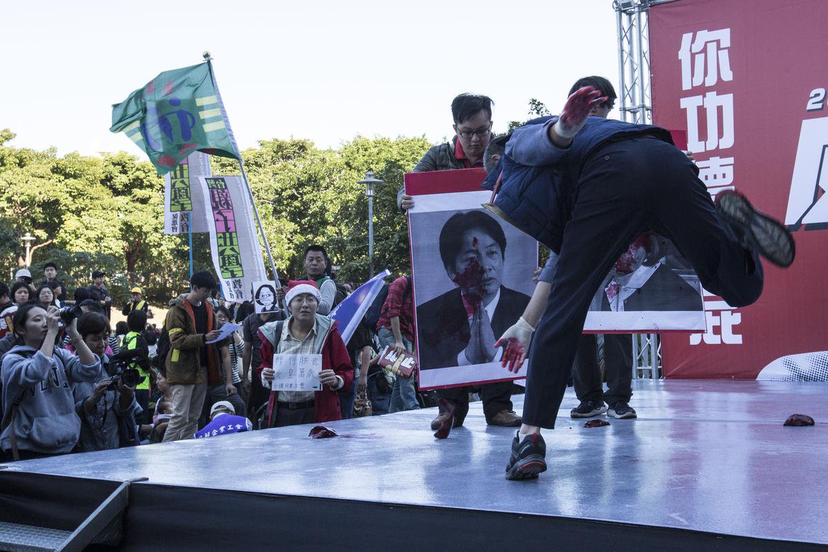 勞團發起萬人反對勞基法修惡遊行,勞工代表把象徵過勞的肝用力砸向行政院長賴清德的照片上。