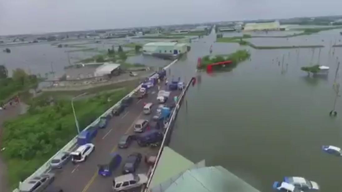 進入掌潭村入口前的積水相當深,許多車輛無法前進,臨停在路邊成了停車場景象。(呂竑毅提供)