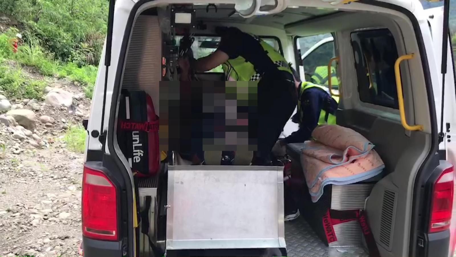 受傷女子意識清醒，經緊急包紮後從溪谷岸邊搬運傷者至救護車上。（圖／TVBS）